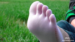 Goddess feet in cute white socks with jeans on the spring grass field Thumb